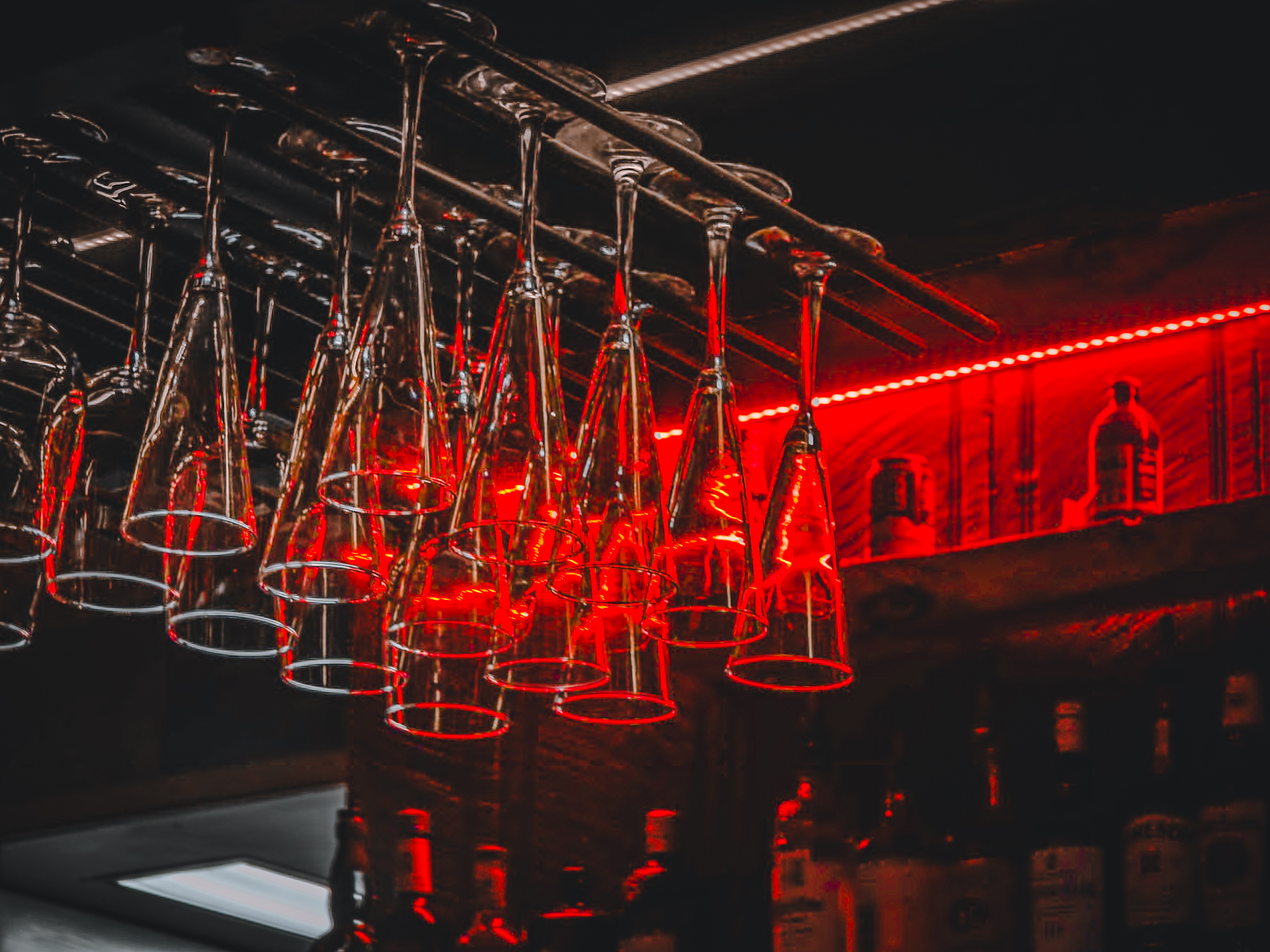 Wine glasses suspended over a bar lit by red neon &mdash; commercial interior photography, Flagstaff Arizona