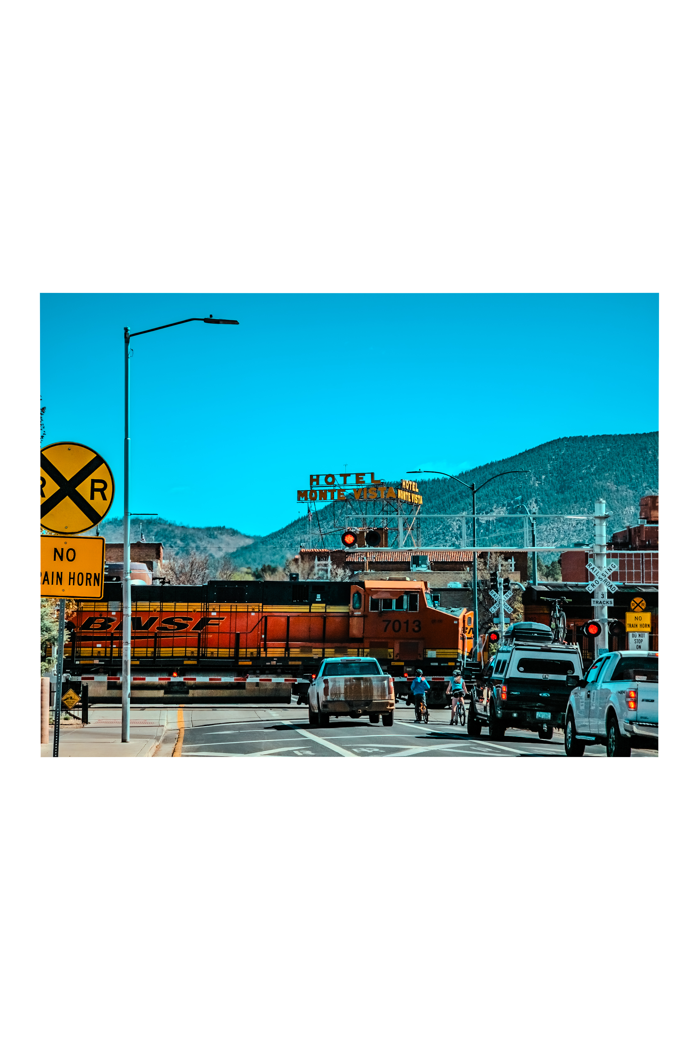 BNSF 7013 rolling through downtown Flagstaff at grade, Hotel Monte Vista behind, San Francisco Peaks above