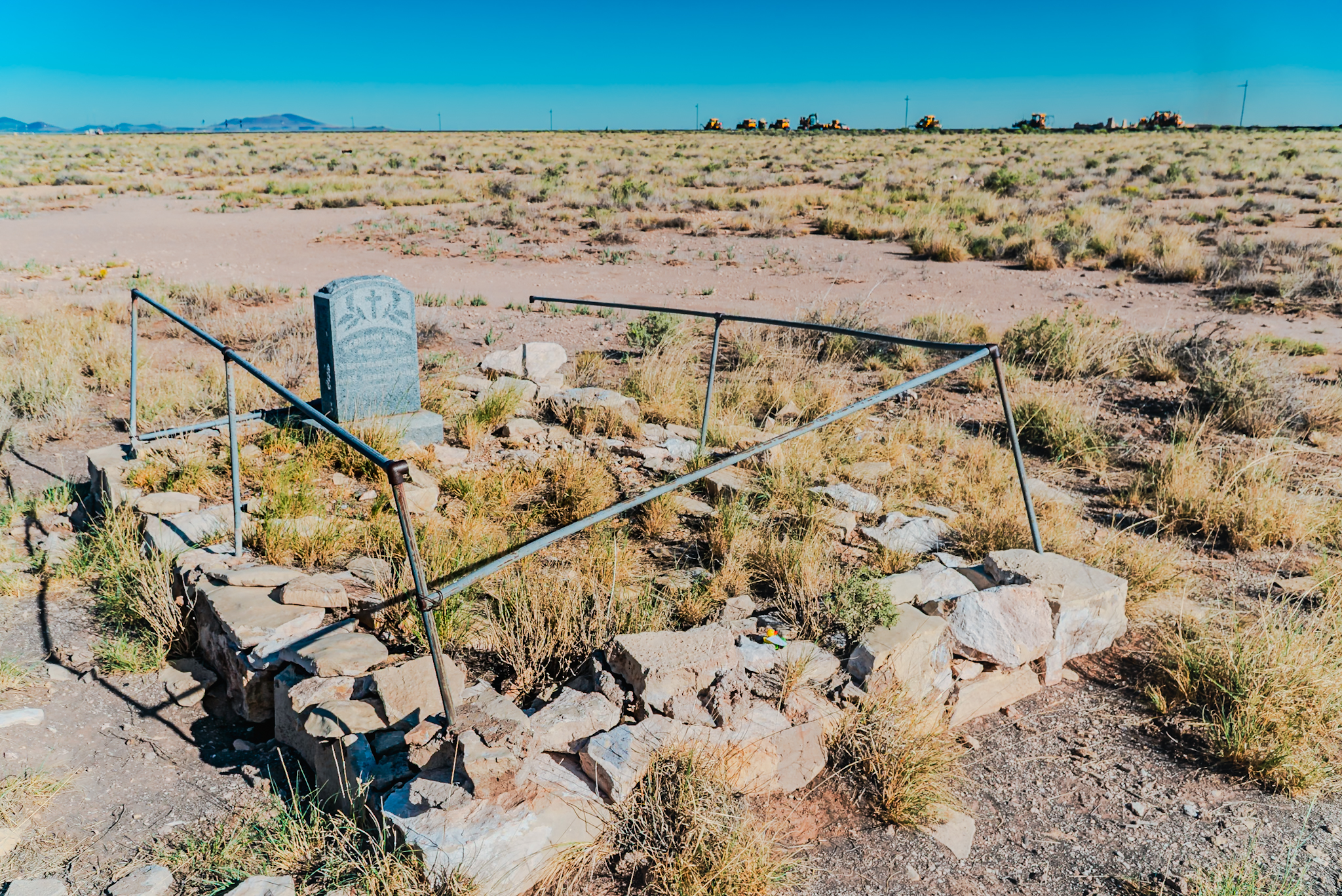 Canyon Diablo German immigrant grave &mdash; full site with iron surround and rock border, vast empty Arizona desert beyond
