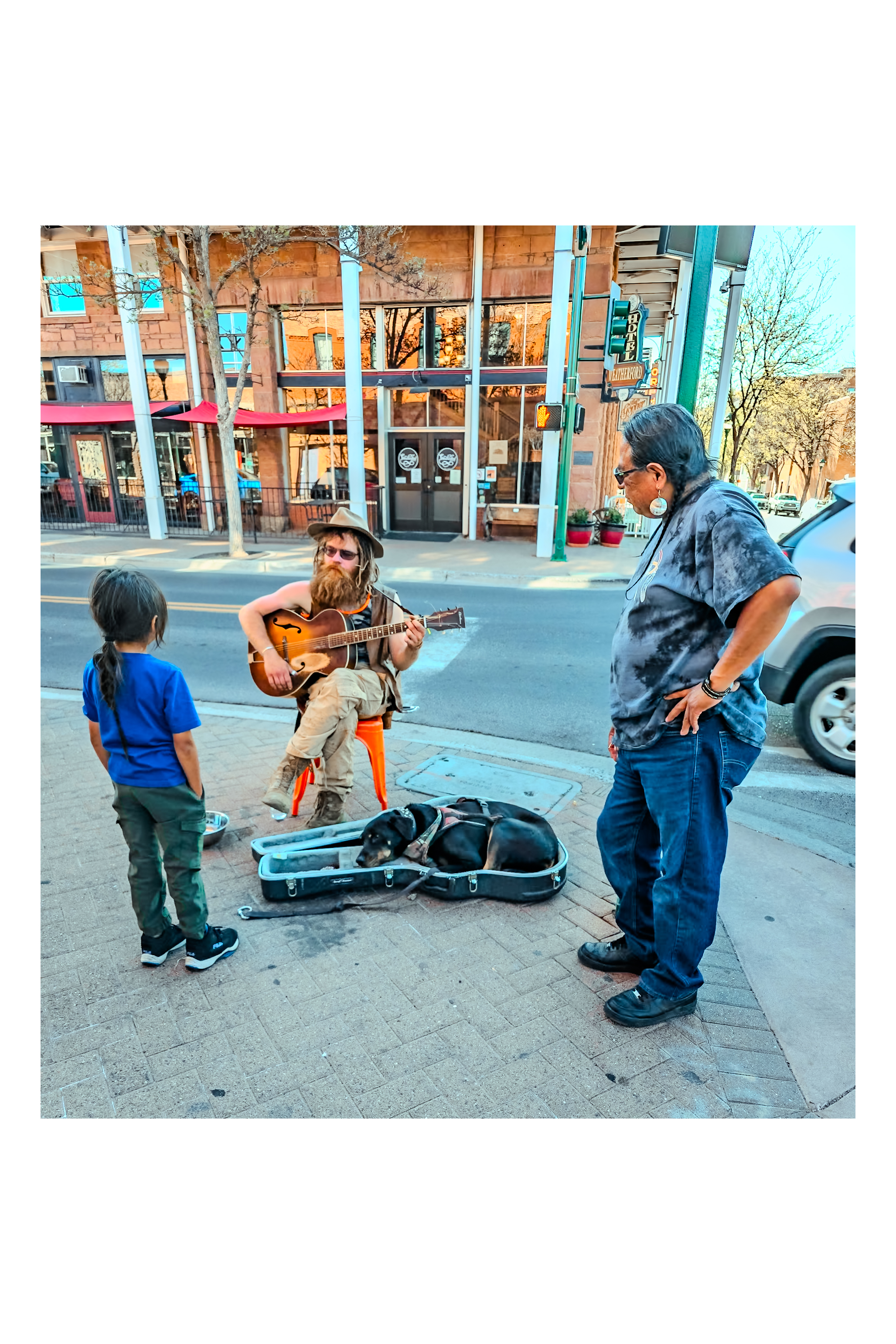 Downtown Flagstaff street musician with dog in guitar case &mdash; Hotel Weatherford behind
